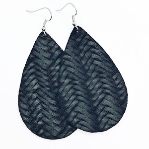 May include: A pair of black leather teardrop earrings with a woven pattern.