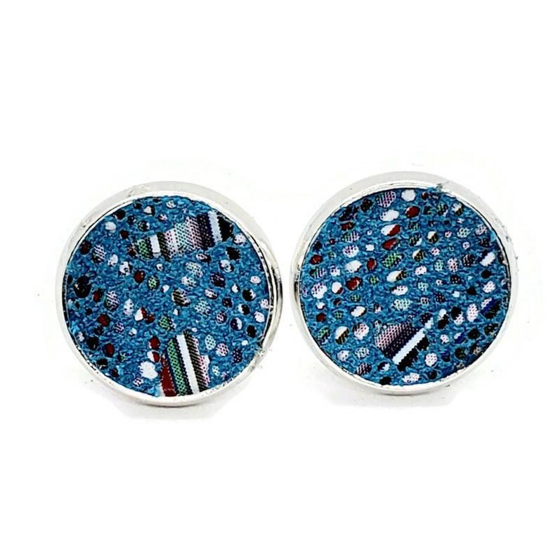 May include: A pair of silver stud earrings with a blue and white patterned design. The pattern features small white dots and a larger geometric pattern in shades of blue, red, and white.