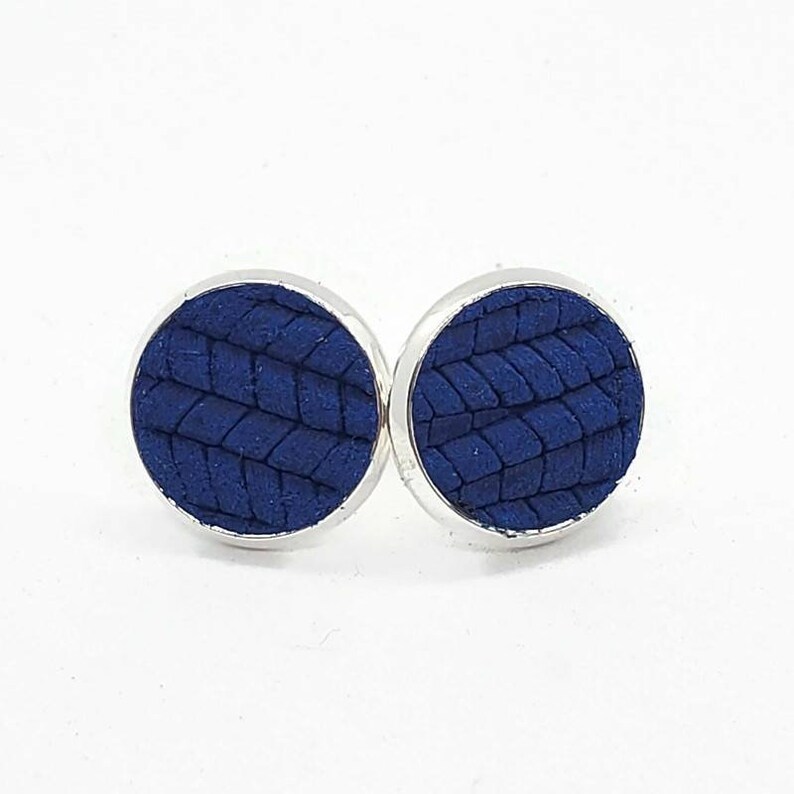 May include: A pair of blue leather earrings with a woven pattern. The earrings are silver-toned and have a circular shape.
