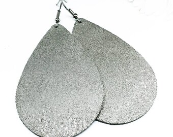 May include: A pair of silver teardrop-shaped earrings with a sparkly finish. The earrings have silver hooks.