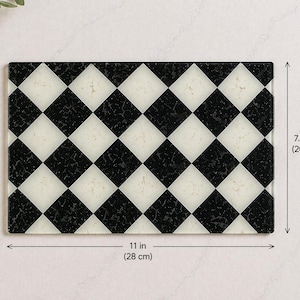 May include: Rectangular cutting board with a black and white checkered pattern. The board measures 11 inches (28 cm) long and 7.87 inches (20 cm) wide. The design features alternating black and white diamond shapes.