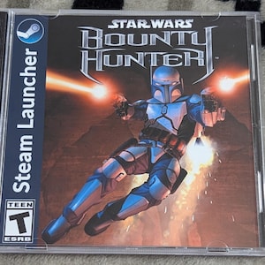 May include: A Star Wars Bounty Hunter PC game in a clear plastic case. The cover art features a character in blue armor firing two blasters. The Steam Launcher logo is on the side, and the ESRB Teen rating is visible.