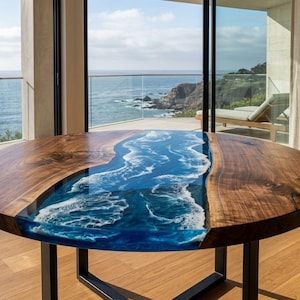 May include: A round dining table featuring a natural wood slab with a live edge and a central blue resin inlay that mimics the appearance of ocean waves with white foam detailing, supported by a black metal frame base.
