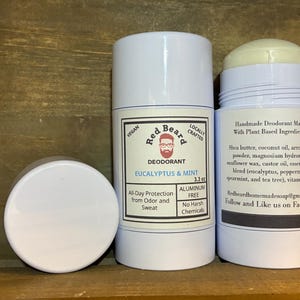 May include: Three white deodorant containers. One is open, showing a solid deodorant stick. The labels state "Eucalyptus & Mint" and "Aluminum Free". The product is handmade with plant-based ingredients. The net weight is 93.5 grams.