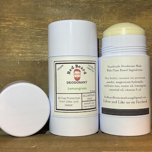 May include: Three white deodorant containers with black text and labels. The labels read "Red Beard" and "Lemongrass". One container is open, revealing a yellow balm. The text on the label says "All-Day Protection from Odor and Sweat".