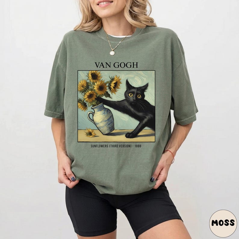 May include: Olive green t-shirt featuring a graphic of a black cat reaching for a vase of sunflowers, inspired by Van Gogh's art. The text "VAN GOGH" and "SUNFLOWERS (THIRD VERSION) - 1888" are printed above and below the image.