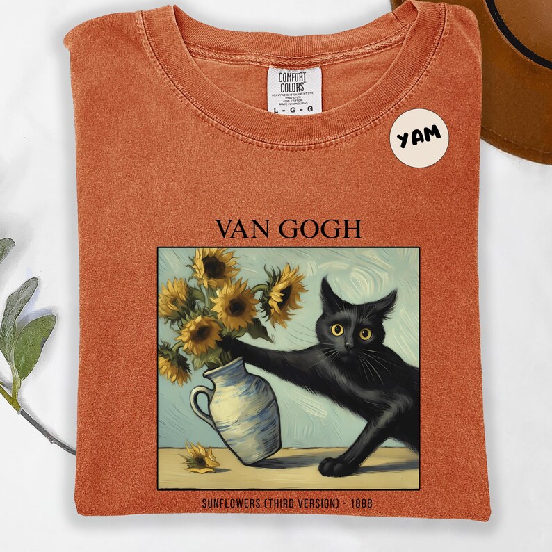 May include: Orange Comfort Colors t-shirt featuring a black cat reaching for a vase of sunflowers, a parody of Van Gogh's painting. The text "VAN GOGH" and "SUNFLOWERS (THIRD VERSION) 1888" are printed on the shirt. A "YAM" sticker is on the shirt.