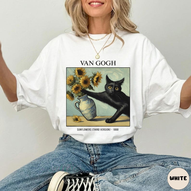 May include: White t-shirt featuring a graphic of a black cat reaching for sunflowers in a vase, inspired by Van Gogh's art. The text "VAN GOGH" is above the image, with "SUNFLOWERS (THIRD VERSION) - 1888" below.