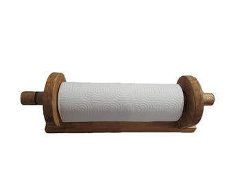 May include: A wooden paper towel holder with a roll of white paper towels. The holder is made of light brown wood and has a simple, rustic design. The paper towel roll is centered.