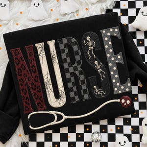 May include: A black long-sleeve shirt featuring the word NURSE in large letters. Each letter has a unique pattern: leopard print, spider webs, checkered, skeletons, and polka dots. A stethoscope with a skull-shaped chest piece is below.