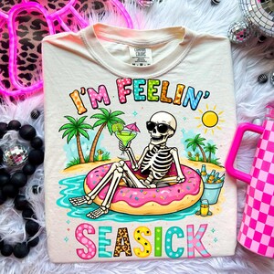 May include: A white ceramic mug with a black handle and the text "But First, Coffee" in a bold, black font. The mug is set against a blurred background, suggesting a cozy setting. The mug appears to be approximately 4 inches tall.