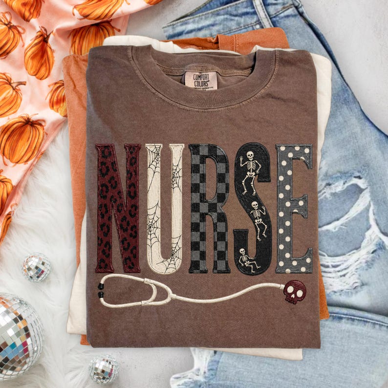 May include: A brown short-sleeve t-shirt featuring the word NURSE in large block letters, each with a different pattern: leopard print, spider webs, black and gray checkers, skeletons, and white polka dots, with a stethoscope graphic below.