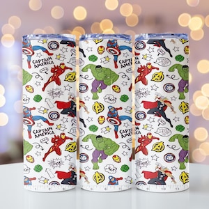 May include: Three white insulated tumblers featuring a repeating pattern of Marvel comic book characters. The design includes Captain America, Iron Man, Hulk, and Thor, with comic book speech bubbles and stars. The tumblers are approximately 25 cm tall.