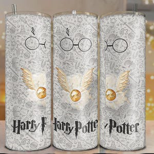 Könnte beinhalten: Drei Edelstahlbecher mit weißem Hintergrund und einem sich wiederholenden Muster von Harry Potter-Symbolen. Jeder Becher hat einen goldenen Schnatz, eine Brille und die Worte "Harry Potter" in Schwarz.