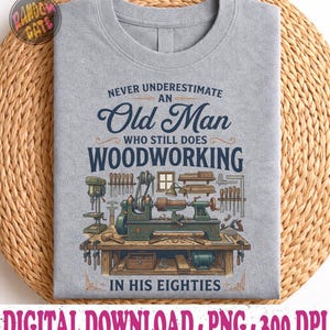 May include: A light gray t-shirt with the text "Never Underestimate an Old Man Who Still Does Woodworking in His Eighties." The shirt features a detailed illustration of woodworking tools and machinery.