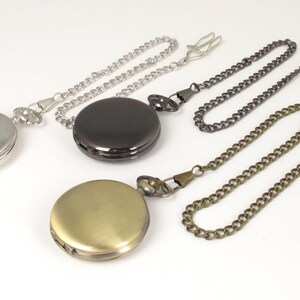 May include: Three pocket watches with chains. The watches are silver, black, and gold. The chains are silver, black, and brass.