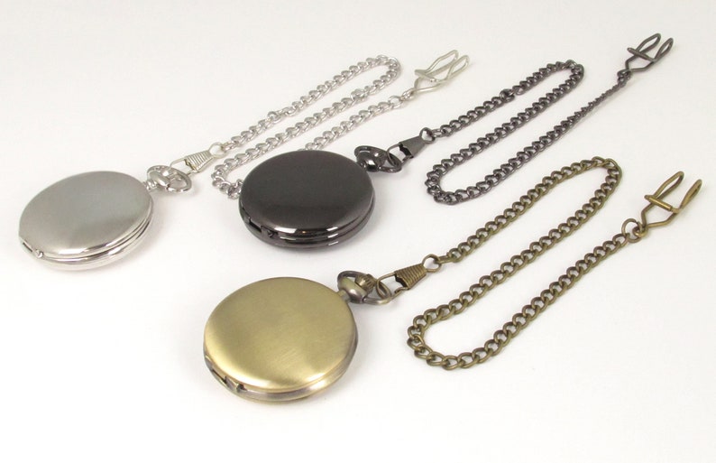 May include: Three pocket watches with chains. The watches are silver, black, and gold. The chains are silver, black, and brass.