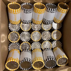 May include: A cardboard box filled with rolls of $10 half dollars. The rolls are white with yellow and black stripes and the text "LOOMIS" and "$10 HALVES". The coins are silver and feature a profile of a person.