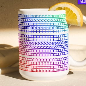 May include: White ceramic mug with a colorful geometric pattern in shades of blue, green, and red. A slice of lemon rests on the rim. The mug has a white handle and the words "BEST SELLER" are in a purple box.