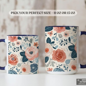 May include: Two white ceramic mugs with a floral design in pink, coral, and blue. The mugs have a navy blue handle and rim. The text "Pick Your Perfect Size - 11 oz or 15 oz" is at the top.
