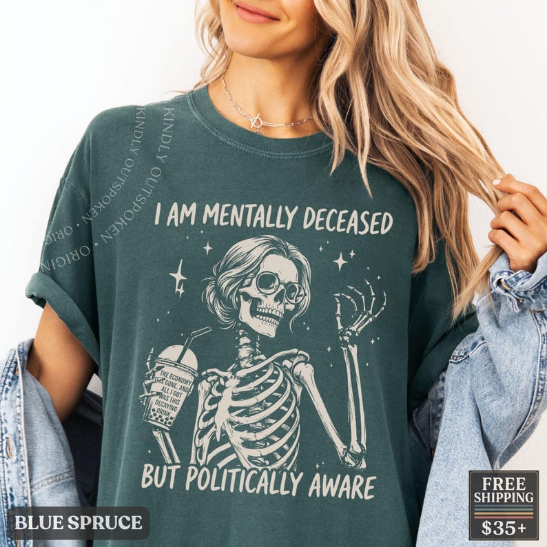 May include: A dark teal short-sleeve t-shirt featuring a graphic of a skeleton wearing glasses and holding a drink. The text reads I AM MENTALLY DECEASED BUT POLITICALLY AWARE. The drink cup has text that reads THE ECONOMY IS GONE AND ALL I GOT WAS THIS DECAYING DRINK.