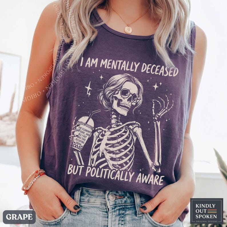 May include: A dark purple sleeveless tank top featuring a white graphic of a skeleton wearing glasses and holding a boba drink. The text reads I AM MENTALLY DECEASED BUT POLITICALLY AWARE. The skeleton is surrounded by small star accents.