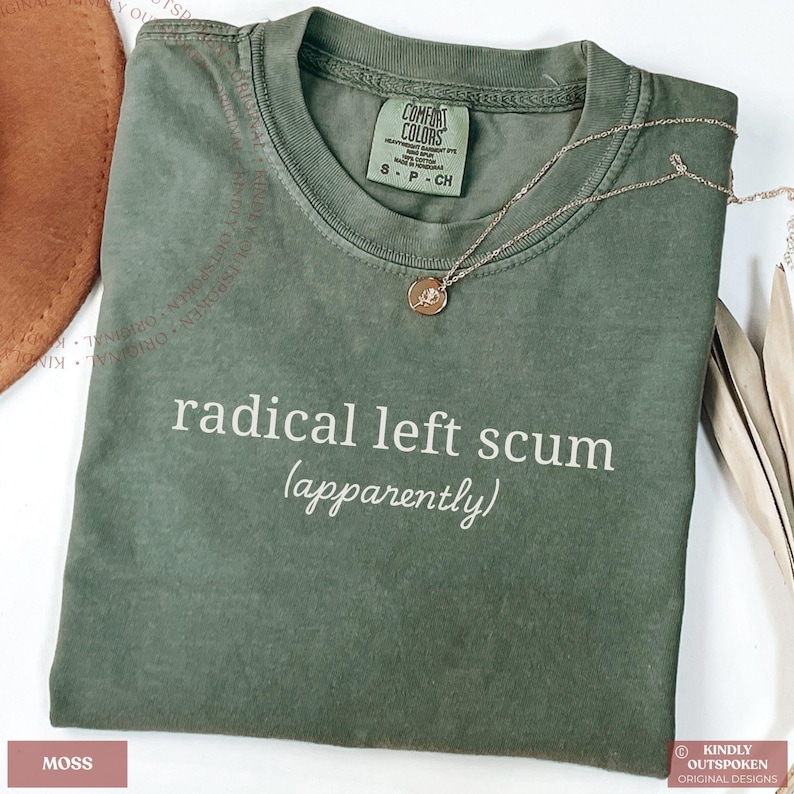 May include: A moss green short-sleeve t-shirt featuring the white text "radical left scum (apparently)" printed on the chest. The shirt has a crew neckline and a Comfort Colors brand label inside the collar, indicating a size small.