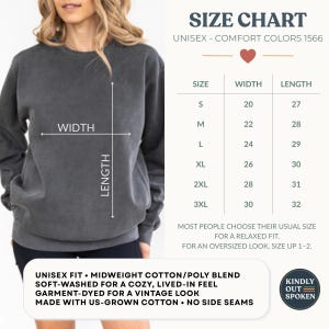 Op de afbeelding: Een antracietgrijze unisex sweatshirt met een maattabel. De tabel toont maten S tot 3XL, met bijbehorende breedte- en lengtematen in centimeters. De sweatshirt is gemaakt van een middengewicht katoen/poly blend, zacht gewassen.