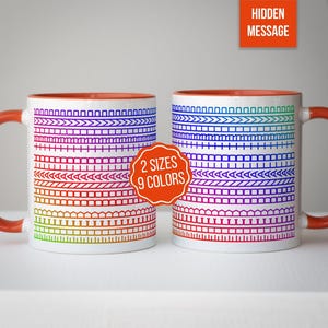 Op de afbeelding: Twee witte keramische mokken met een regenboogkleurig ontwerp. De mokken hebben oranje handvatten en interieurs. Het ontwerp bevat verschillende geometrische patronen in een spectrum van kleuren. Collectie met 2 maten en 9 kleuren.