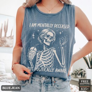 May include: A blue sleeveless tank top featuring a white graphic of a skeleton wearing sunglasses and holding a boba drink. The text reads I AM MENTALLY DECEASED BUT POLITICALLY AWARE, with the cup text stating THE ECONOMY IS GONE AND ALL I GOT WAS THIS DECAYING DRINK.