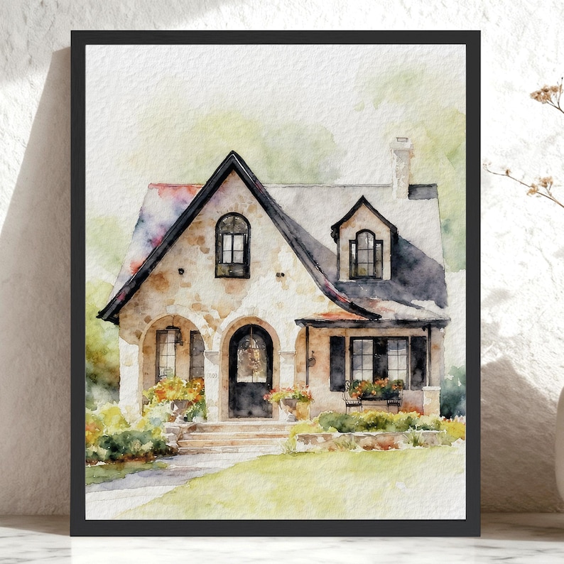 May include: A framed watercolor painting of a two-story stone house with a dark roof, a central arched doorway, multiple windows, and a chimney. The house is surrounded by green landscaping and colorful flowers, all set within a black frame.