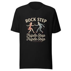 Può includere: T-shirt nero con grafica in stile vintage. Il design presenta una coppia che balla e le parole "ROCK STEP" sopra "Triple Step Triple Step". La freccia punta verso destra. I ballerini sono in movimento, la donna con un vestito rosa e l'uomo con un abito grigio.