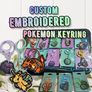 May include: A collection of custom embroidered Pokemon keyrings featuring various pixelated character designs. Each keyring includes a colorful plastic clasp and is displayed on a small card, with some packaged in clear plastic sleeves.