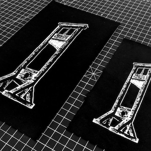 May include: Two black fabric patches with a white outline of a guillotine.