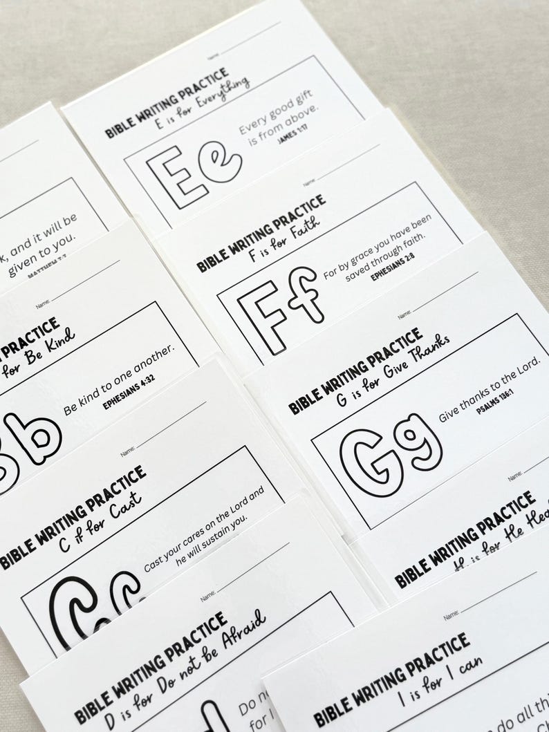 May include: A stack of white Bible writing practice cards. Each card features a letter of the alphabet, a corresponding word, and a Bible verse. The letters are outlined in black, with the words and verses printed in black.