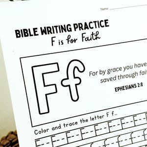 May include: A white Bible writing practice sheet with the text "BIBLE WRITING PRACTICE F is for Faith". The sheet includes a large outlined letter "F" and lines for tracing the letter. The text "For by grace you have saved through faith" is also present.