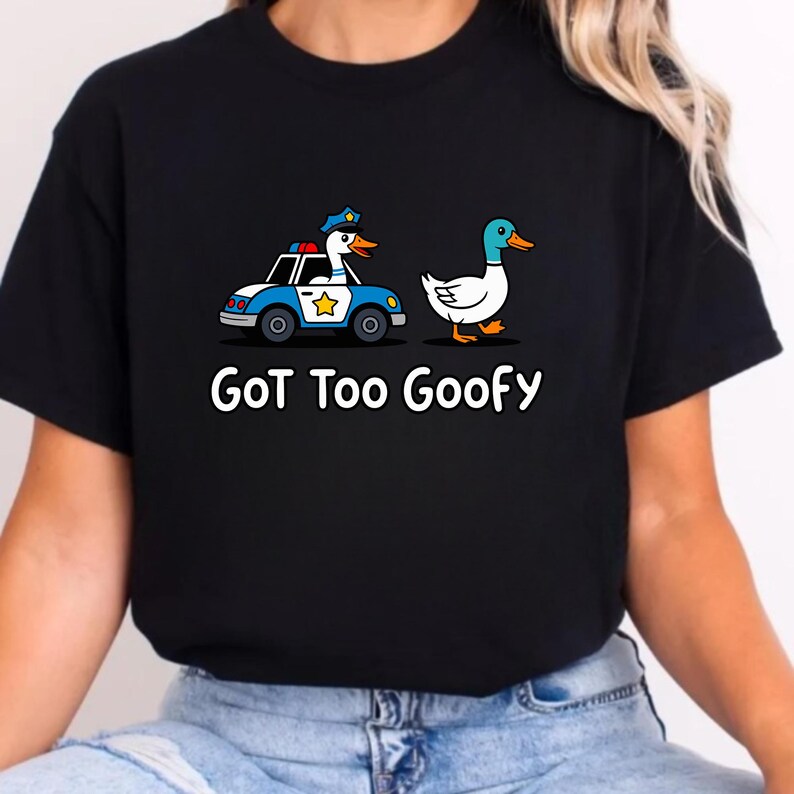 May include: Black t-shirt with a cartoon duck driving a police car and another duck walking. The text "GoT Too Goofy" is printed in white below the graphic. The police car is blue and white with a gold star on the side.