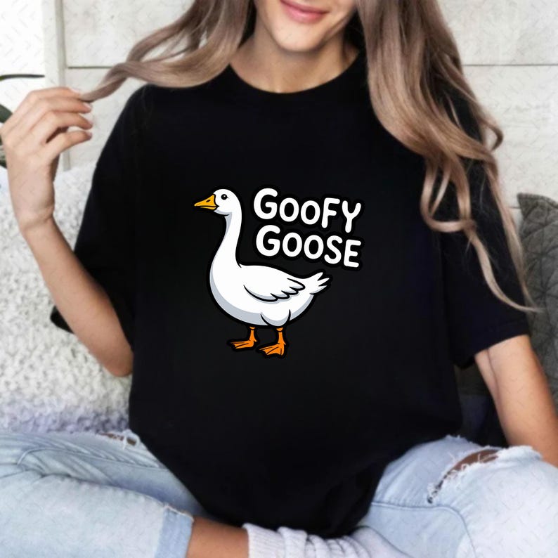 May include: Black t-shirt featuring a cartoon goose with the text "Goofy Goose" in white. The goose is white with orange feet and a yellow beak. The shirt is a casual style.