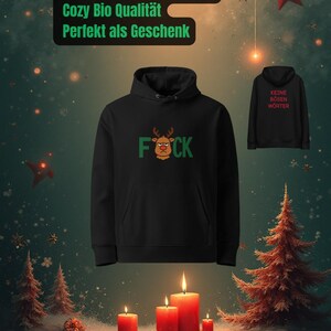 Peut inclure: Un sweat &agrave; capuche noir avec un motif de renne et le mot "FOCK" en vert. L'image pr&eacute;sente &eacute;galement un deuxi&egrave;me sweat &agrave; capuche avec le texte "KEINE B&Ouml;SEN W&Ouml;RTER". Sc&egrave;ne festive avec des bougies, des sapins et le texte "Frohes FOCK Weihnachten".