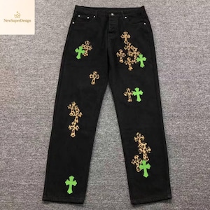 Op de afbeelding: Zwarte denim jeans met luipaardprint en neon groene kruisapplicaties. De jeans hebben een knoopsluiting en een klassiek ontwerp met vijf zakken. Het NewSuperDesign-logo staat in de linkerbovenhoek.