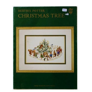 May include: A Beatrix Potter Christmas Tree cross stitch pattern booklet with a dark green cover. The cover features a central illustration of anthropomorphic animals dancing around a decorated Christmas tree, framed in a gold-colored border.