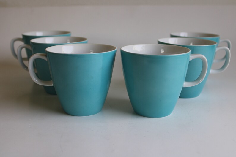 Pu&ograve; includere: Sei tazze in ceramica blu turchese con interno bianco. Le tazze hanno una forma arrotondata e un manico sul lato destro.