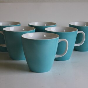 Pu&ograve; includere: Sei tazze in ceramica blu turchese con interno bianco. Le tazze hanno una forma arrotondata e un manico sul lato destro.