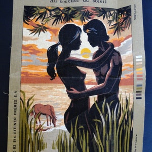 May include: Needlepoint canvas featuring a couple embracing at sunset, with a horse grazing nearby. The scene is framed by tall grass and foliage, with the text "Au coucher du soleil" at the top. The canvas is marked "Royal Paris" and "Made in France."