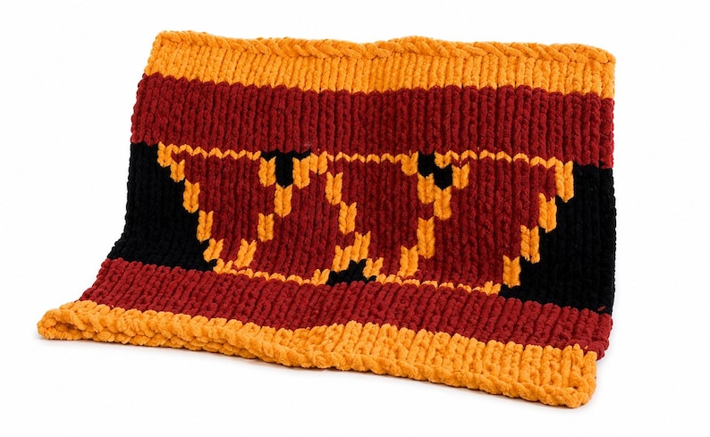 May include: A rectangular knitted cowl featuring horizontal stripes in orange, dark red, and black. The center section displays a large, stylized letter W pattern created with orange yarn against a dark red and black background.