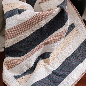 Peut inclure: Ensemble de trois mugs en céramique crème tachetée. Chaque mug présente un motif floral peint à la main en bleu, vert et jaune. Les mugs ont une forme arrondie et une anse.