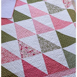 May include: A handmade quilt with a geometric pattern of triangles in shades of pink, green, and white. The quilt features various floral and patterned fabrics, with a red and white gingham border. The quilt is machine quilted.