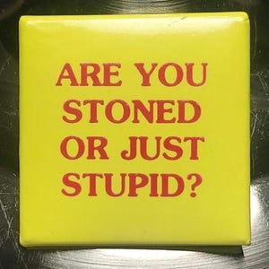 May include: Yellow square button with the text "ARE YOU STONED OR JUST STUPID?" in red letters. The button has a glossy finish and a simple, bold design. The text is centered on the button.