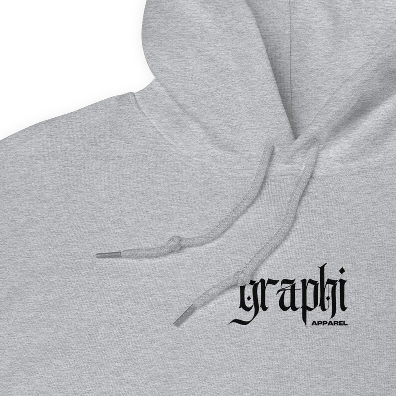 May include: A light grey hoodie with a drawstring and hood. The black text "graphi" is printed on the front, with "APPAREL" below it. The hoodie is made of a soft material.