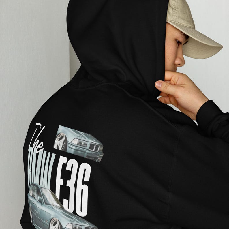 K&ouml;nnte beinhalten: Schwarzer Kapuzenpullover mit einem Autodesign und dem Text "The BMW E36" in Wei&szlig;. Das Design umfasst zwei Autoillustrationen. Der Hoodie hat eine Kapuze und lange &Auml;rmel.